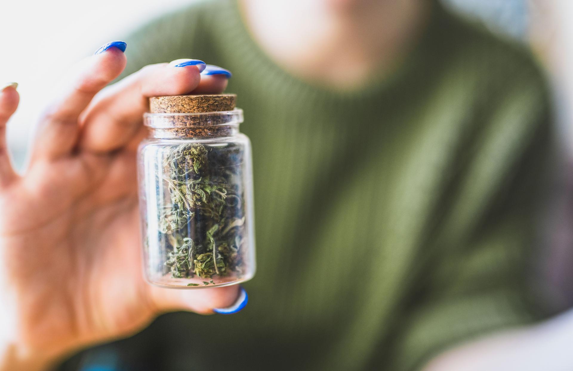 Woman holding jar full of marijuana.